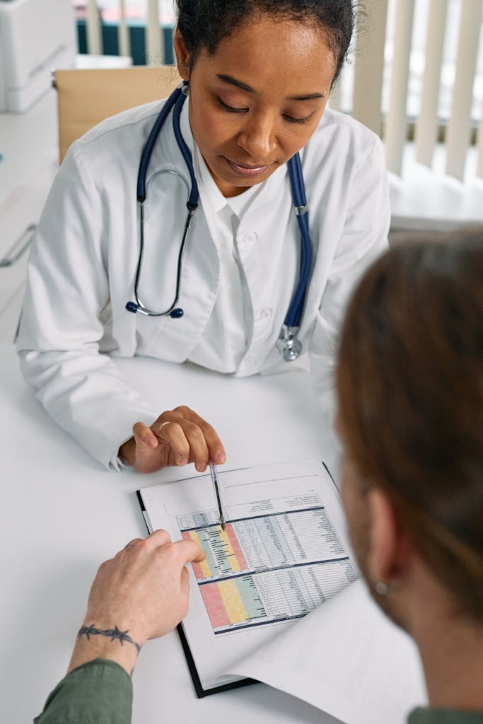 Doctor consulting patient in modern medical clinic, reviewing health chart for diagnosis.