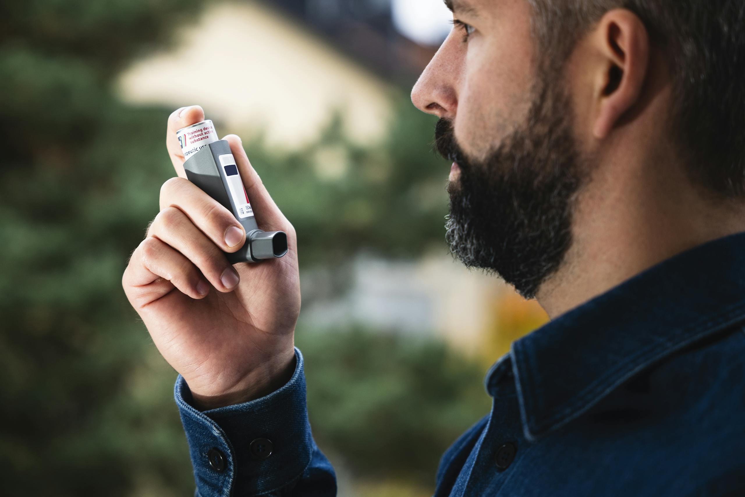 AERD (Aspirin Exacerbated Respiratory Disease) Adult man uses inhaler outdoors for asthma relief, focusing on respiratory health.