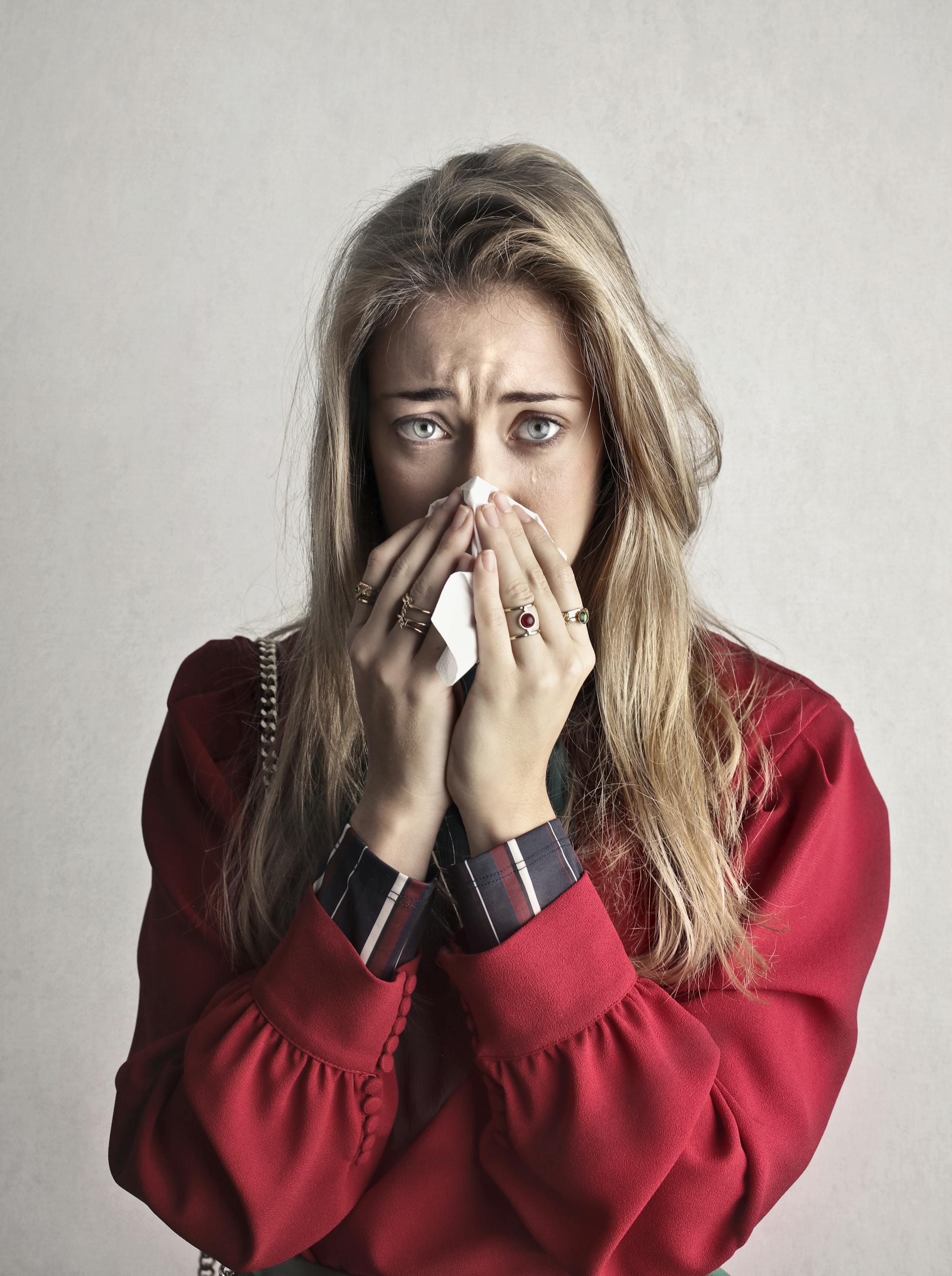 AERD (Aspirin Exacerbated Respiratory Disease) Portrait of a woman sneezing with a tissue, depicting flu symptoms.
